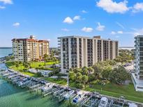Stunning aerial view of waterfront condos, marina, and lush landscaping under a bright, partly cloudy sky at 690 Island Way # 1003, Clearwater Beach, FL 33767