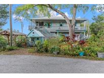 Charming two-story home with a metal roof, dual balconies, and lush, colorful landscaping at 8117 River Point Dr, Weeki Wachee, FL 34607
