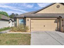 Two-car garage and well-maintained landscaping enhance the curb appeal of this charming home at 8949 Southern Charm Cir, Brooksville, FL 34613