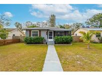Charming single-story home with gray siding, decorative shutters, manicured hedges and a walkway leading to the front door at 2454 15Th N Ave, St Petersburg, FL 33713