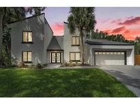 Contemporary two-story home with a well-manicured lawn, palm trees and modern architectural design at 4520 Pine Hollow Dr, Tampa, FL 33624