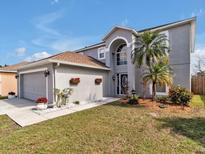 Charming two-story home with a well-manicured lawn, complemented by palm trees and flower boxes at 5337 Treig Ln, Wesley Chapel, FL 33545