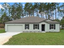 Charming single-story home features a well-maintained lawn, neutral paint, a two-car garage, and classic black shutters at 12341 Filbert Rd, Weeki Wachee, FL 34614