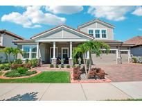 Charming two-story home featuring a manicured lawn, brick driveway, and an attached two-car garage at 13069 Paddock Wood Pl, Riverview, FL 33579