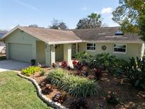 Charming one-story home features a lush landscaped front yard and attached one car garage at 1363 Overlea Dr, Dunedin, FL 34698