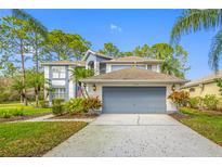 Charming two-story home featuring a large garage, well-kept lawn and mature landscaping at 15702 Muirfield Dr, Odessa, FL 33556