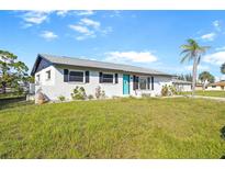 Charming single-story home with a well-maintained lawn and inviting blue front door at 184 Garden Nw Ave, Port Charlotte, FL 33952