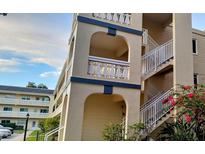 Three story building with balconies with archways, a staircase and pink flowers at 2256 Spanish Dr # 42, Clearwater, FL 33763