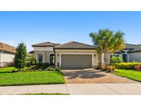 Charming single-story home featuring manicured landscaping, a tile roof, and a brick-paved driveway at 4228 Isonzo Way, Wesley Chapel, FL 33543