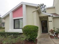 Charming home featuring light-yellow stucco, pink accent tiles, a black front door and a well-manicured shrub in the front at 8055 Picketts Ct # 1, Weeki Wachee, FL 34613