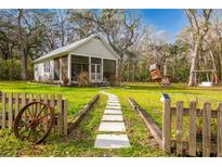 Charming cottage home with a stone path leading to a screened porch and a decorative rustic yard at 13381 Glory Ln, Brooksville, FL 34614