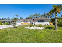 Charming single-story home with well-manicured lawn, front yard landscaping, and a classic American flag at 14265 Page Ave, Largo, FL 33774