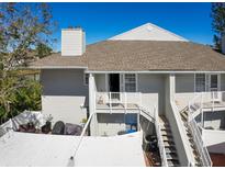Two-story condo featuring a brown roof, white siding, a balcony, a ground-floor patio, stairs, and an outdoor grilling area at 8350 Savannah Trace Cir # 1808, Tampa, FL 33615