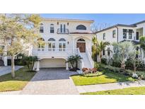 Elegant two-story home features a brick driveway, a white facade, arched windows and a balcony at 102 Adriatic Ave, Tampa, FL 33606