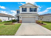 Charming two-story home with a two car garage, blue shutters and well manicured lawn on a sunny day at 10432 High Noon Trl, Parrish, FL 34219