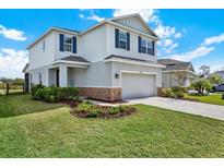Two-story home with a two car garage, blue shutters, well manicured lawn and stone accents at 10432 High Noon Trl, Parrish, FL 34219