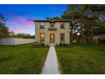 Charming two-story home with a manicured lawn and welcoming walkway leading to the front entrance under a twilight sky at 7125 6Th N Ave, St Petersburg, FL 33710