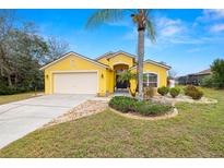 Charming yellow single-story home with a two-car garage and a well-maintained front yard with lovely landscaping at 10454 Crestfield Dr, Riverview, FL 33569