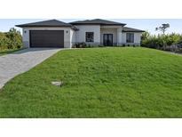 Modern one-story home with a dark roof, a two-car garage, and a well-manicured front yard at 14207 Fort Worth Cir, Port Charlotte, FL 33981