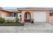Charming home featuring a white garage door, arched entryway and well-maintained landscaping at 10467 Larchmont N Pl, Pinellas Park, FL 33782