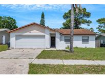 Charming one-story home with a well-maintained lawn and attached garage, perfect for a starter home or downsizing at 105 Lotus Cir, Safety Harbor, FL 34695