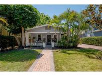 Charming bungalow featuring a brick walkway, manicured lawn, and lush tropical landscaping at 3116 W Wallcraft, Tampa, FL 33611