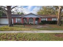 Charming red brick home featuring three arched entryways and a well-manicured lawn at 3817 Twilight Dr, Valrico, FL 33594