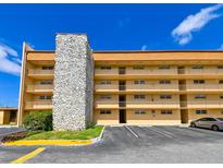 A tan condo building with parking, stone exterior design, and multiple floors of balconies at 5820 N Church Ave # 430, Tampa, FL 33614