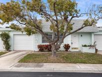 Charming single-story home featuring a well-maintained lawn, mature tree, and attached garage. The house is painted in a soft, neutral color at 8460 Calais N # 8406, Pinellas Park, FL 33781