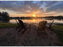 Backyard includes a fire pit with seating, with a beautiful water view as the sun sets in the background at 1301 Jen Ma Jo Ln, Lutz, FL 33549