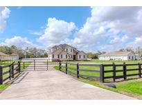 A charming two-story home features black shutters, mature trees, and a long, gated driveway at 4411 Miley Rd, Plant City, FL 33565