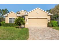 Charming home with a two-car garage, brick driveway, well-manicured lawn and verdant shrubbery at 10105 Holly Berry Dr, Weeki Wachee, FL 34613