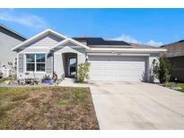 Charming one-story home featuring a well-manicured lawn, two car garage, and solar panels on the roof at 1014 Coastal Hammock Ave, Ruskin, FL 33570