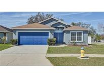Charming single-story home with a well-maintained lawn and a blue garage door at 11213 Southwind Lake Dr, Gibsonton, FL 33534