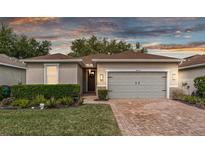 Charming single-story home with a well-manicured lawn, brick driveway and attached two-car garage at 25325 Welsh Poppy Way, Land O Lakes, FL 34639