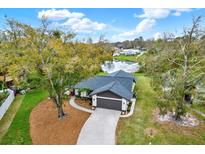Inviting home with well-maintained landscaping and water view, complemented by a concrete driveway and gray garage door at 3944 Sprucewood Pl, Land O Lakes, FL 34639