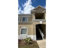 Beige two-story condo building exterior featuring a stairwell entrance and sunny skies above at 6011 Skydale Way # 101, Riverview, FL 33578