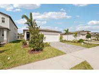 Charming one-story home boasts lush landscaping, a brick driveway, and an attached two-car garage at 129 Whiteland Bnd, Nokomis, FL 34275