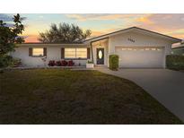 Charming single story home with a well-manicured lawn and mature trees against a lovely sunset at 1464 S Evergreen Ave, Clearwater, FL 33756