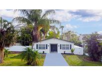 Charming single-story home featuring a well-manicured lawn, palm trees, and a freshly painted driveway at 715 Virginia Ave, Tarpon Springs, FL 34689