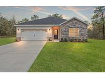 Charming single-story home with stone accents, well-maintained lawn and a two car garage at 13065 Tinamou Ave, Weeki Wachee, FL 34614