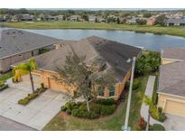 Stunning aerial view of tan house by pond, showcasing its tile roof, lush landscaping, and proximity to community amenities at 2313 Nottingham Greens Dr # 2313, Sun City Center, FL 33573