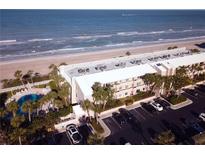 An aerial view showcases a beachfront condo with a pool, parking, and stunning ocean views at 3400 Gulf Blvd # 304, Belleair Beach, FL 33786