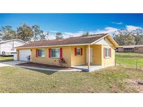Charming single-story home with yellow siding, red shutters, and a well-maintained front lawn at 37143 Janet Cir, Dade City, FL 33525