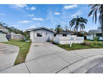 Charming single story home with a well manicured lawn, concrete driveway, and white picket fence at 415 Maplewood Cir, Oldsmar, FL 34677