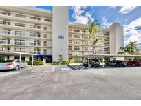 Exterior view of a condo building with parking and landscaping on a sunny day at 1324 Pasadena S Ave # 204, South Pasadena, FL 33707