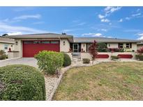 Charming home with a red garage door, landscaped yard, and vibrant flowerbeds enhancing its curb appeal at 1518 New Bedford Dr, Sun City Center, FL 33573