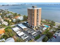 Stunning aerial view of a red brick highrise condo building next to a bay with a parking area and pool at 4015 Bayshore Blvd # 11A, Tampa, FL 33611