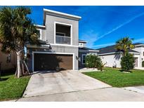 Contemporary two-story home featuring a balcony, attached garage, and a well-manicured lawn at 5934 Maidenstone Way, Palmetto, FL 34221