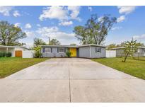 Charming single-story home with a yellow front door and a spacious concrete driveway at 7030 19Th N Way, St Petersburg, FL 33702